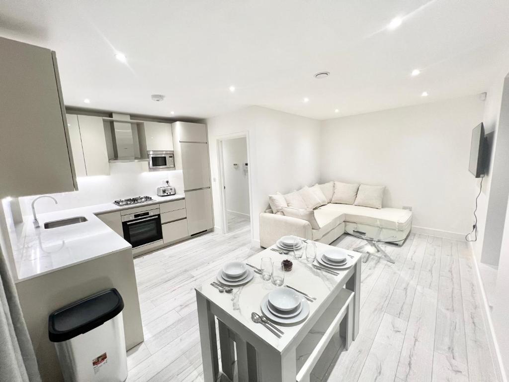 Sala e cozinha compartilhada do Queens Luxury Apartments com uma cozinha completa, uma pequena mesa com quatro lugares, um sofá com almofadas e uma televisão