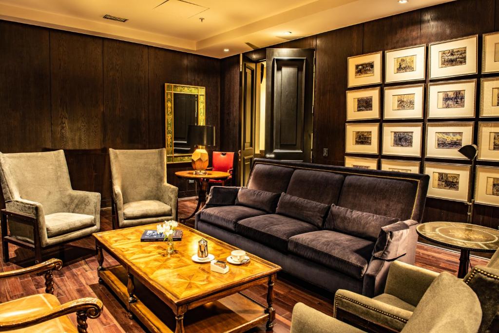 Sala de estar do The Singular com sofá preto, poltronas cinzas e mesa de madeira no centro. Representa hotéis boutique em Santiago.