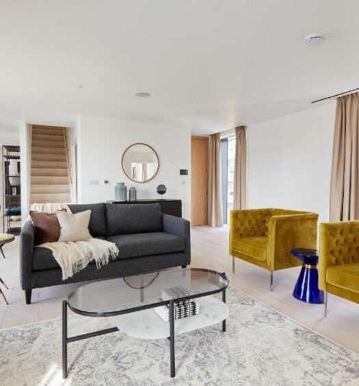 Sala de estar do Southwark by Q Apartments com duas poltronas, janelas amplas com cortinas, um sofá com dois lugares, uma mesa de centro e itens de decoração, para representar airbnb em Londres