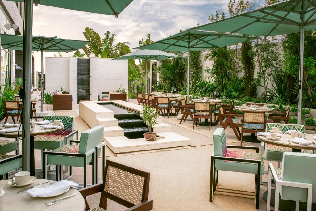 terraço do ette luxury hotel & spa, um dos hotéis de luxo em Orlando, com mesas e cadeiras modernas em detalhes demadeira e verdes, uma fonte no centro com escadas e ambiente coberto com plantas