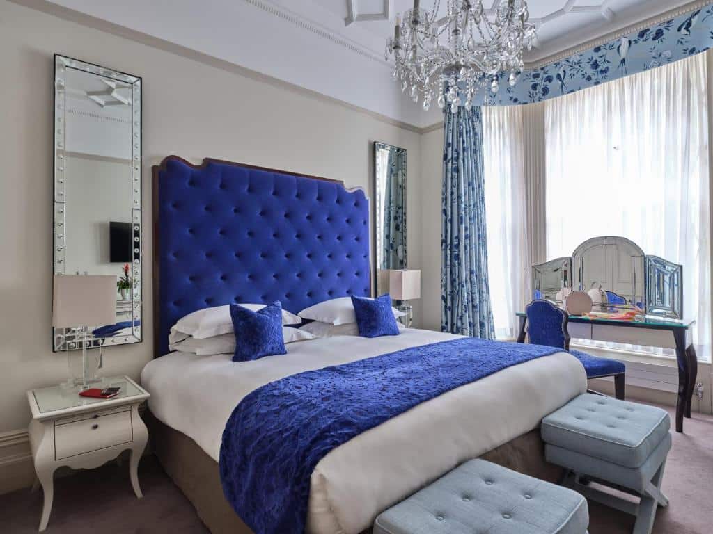 Quarto do The Apartments by The Sloane Club com uma cama de casal, dois espelhos, um lustre, uma jenal com cortinas, uma penteadeira, dois bufes e duas mesinhas de cabeceira