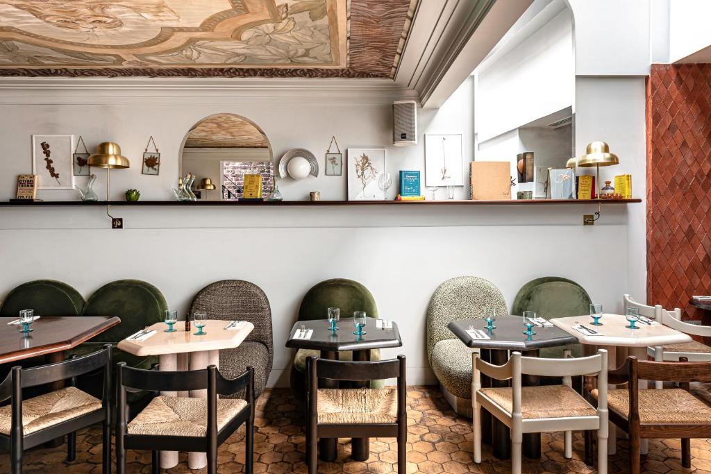 Área para refeições do The Henrietta Hotel com mesas de madeira, poltronas em tons de verde, cadeiras de madeira e um balcão com alguns itens de decoração, para representar hotéis em Londres para brasileiros