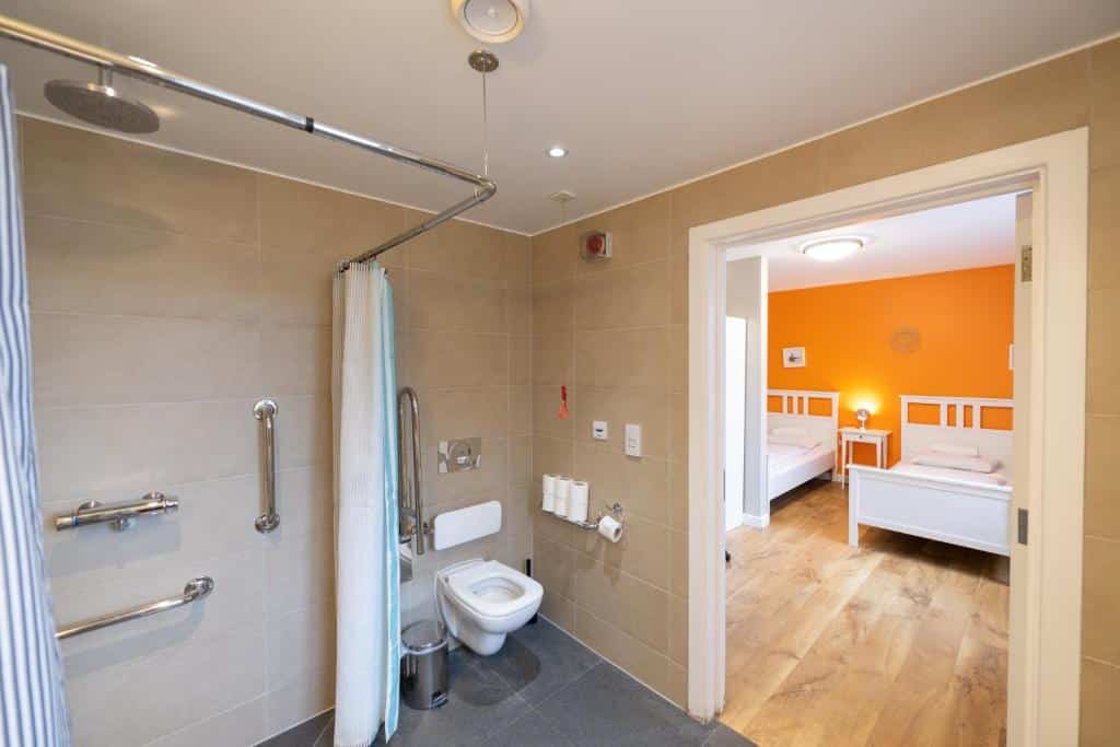Banheiro adaptado do Wombat’s City Hostel London com barras de apoio em todos os locais, porta ampla para passar uma cadeira de rodas e cordão de emergência