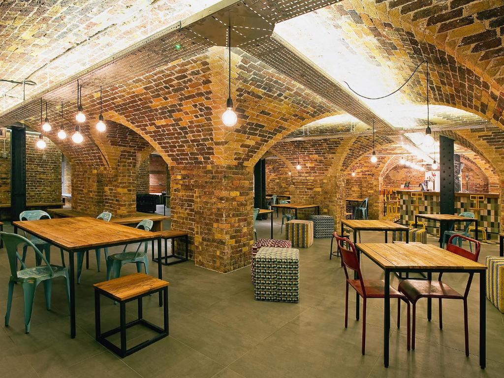 Área de refeições do Wombat's City Hostel London com teto de pedra, com algumas mesas e cadeiras, para representar hostels em Londres