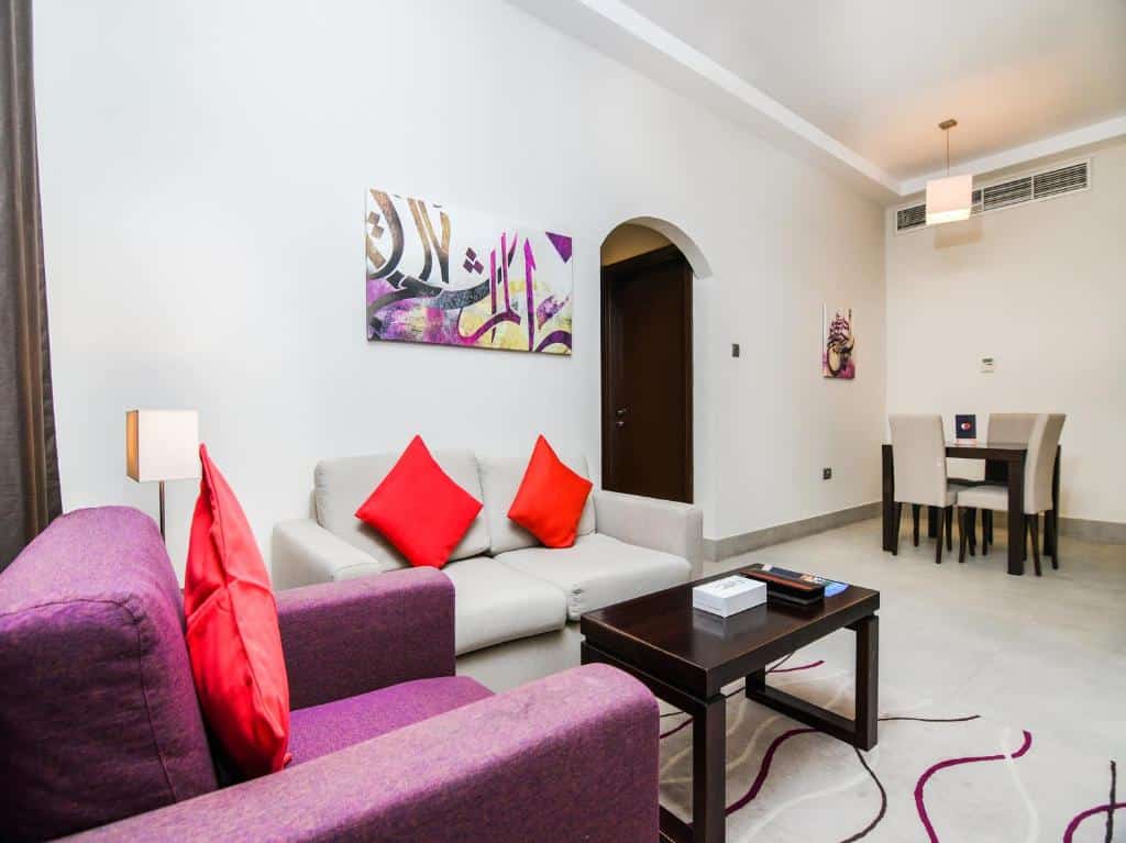 Sala de estar do Action Hotel Ras Al Khaimah com uma mesa quadrada com quatro cadeiras, dois sofás com almofadas e uma mesinha de centro