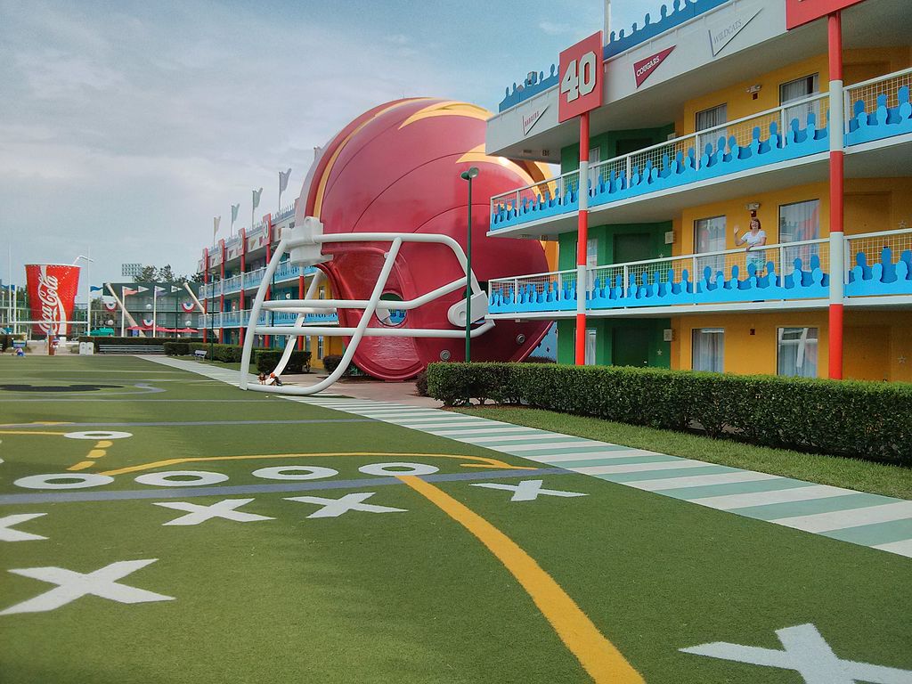 área externa que imita um campo de futebol americano com jardas desenhas no chão e um capacete enorme no Disney's All-Star Sports Resort
