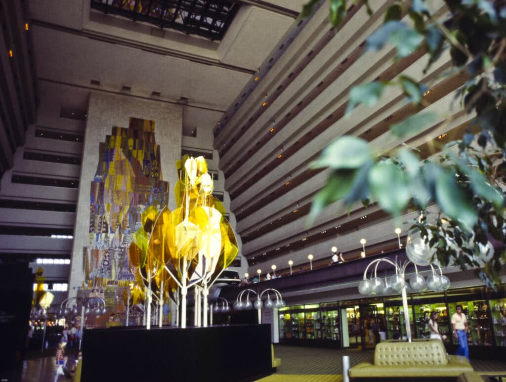 área interna do Disney's Contemporary Resort com obras de arte douradas em ambiente alto e moderno com linhas retas e um enorme mural de 27 metros de altura delicadamente pintado e colorido