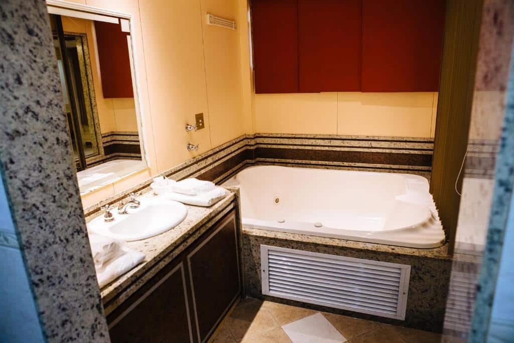 Uma pia e uma banheira de hidromassagem, no banheiro do hotel. Foto para ilustrar post sobre hotéis perto do Consulado Americano no Rio de Janeiro.
