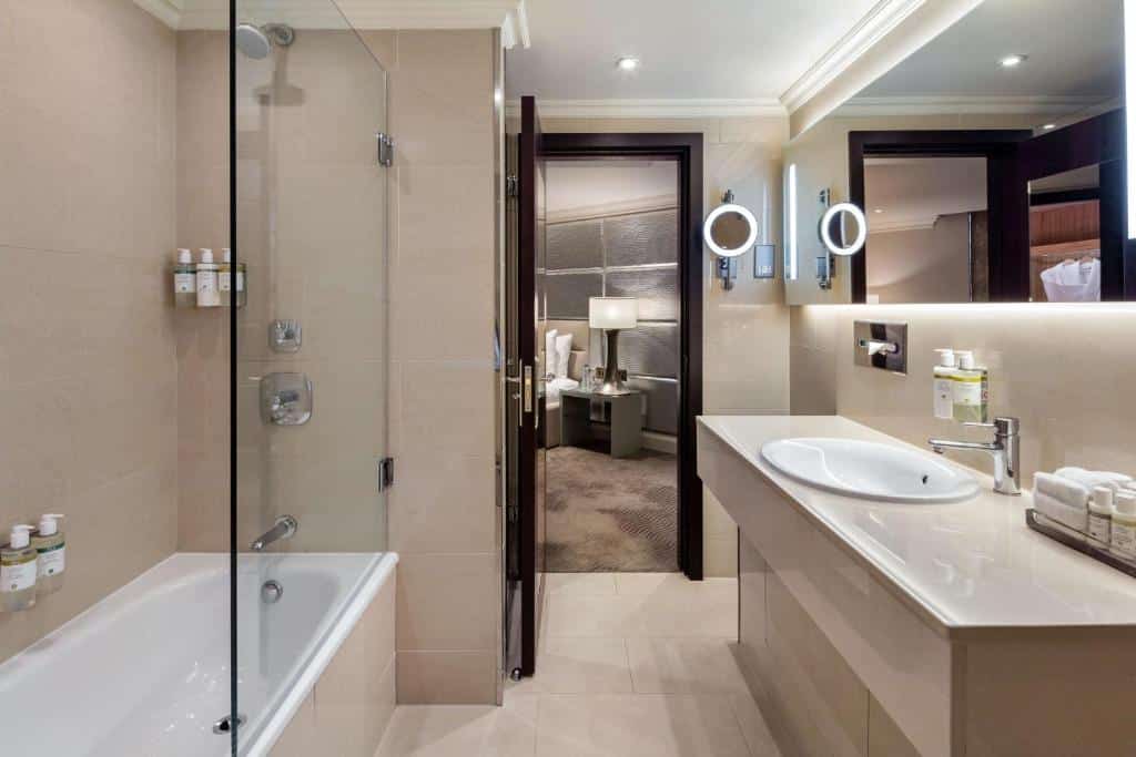 Banheiro do Radisson Blu Edwardian Mercer Street Hotel, London com uma banheira e um box de vidro, uma pia ampla e um espelho amplo também, para representar hotéis em Londres para brasileiros