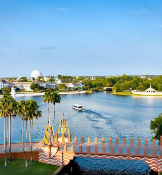vista de um lago com um barco que passa abaixo de uma ponte temática e que liga o Epcot ao Walt Disney World Swan Reserve, um dos hotéis da Disney em Orlando