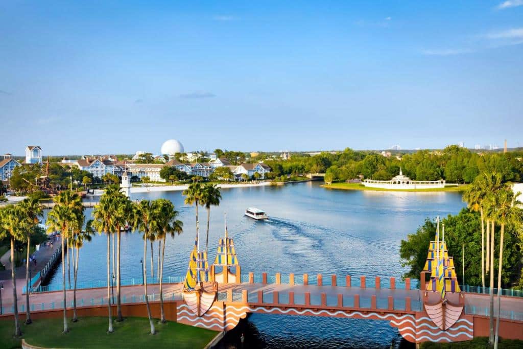 vista de um lago com um barco que passa abaixo de uma ponte temática e que liga o Epcot ao Walt Disney World Swan Reserve