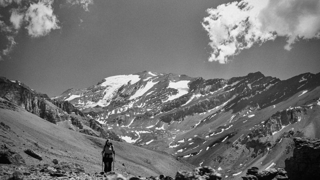 Imagem preto e branco de uma mulher subindo as Cordilheira dos Andes em Santiago.