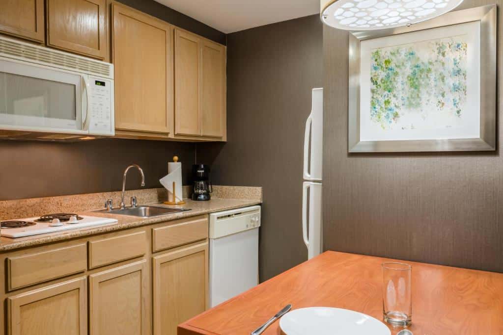 cozinha com balcão, armários de madeira e itens brancos como geladeira, fogão e micro-ondas no Homewood Suites by Hilton Orlando-Nearest to Universal Studios, um dos hotéis com cozinha em Orlando