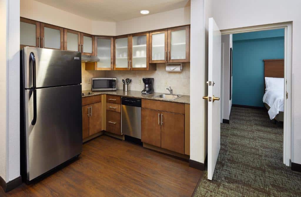 cozinha com geladeira, forno, micro-ondas e armários com tons de madeira no Staybridge Suites Orlando South, an IHG Hotel, um dos hotéis com cozinha em Orlando