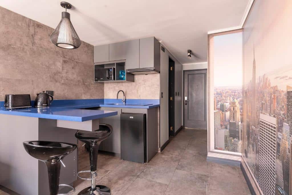 Cozinha do Encomenderos Design Tech Comfort & Location com balcão de mármore azul, com frigobar, micro-ondas pia. Representa aluguel de temporada em Santiago.