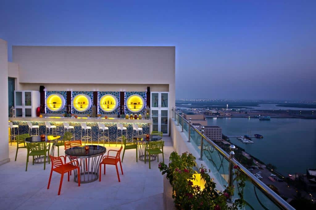 Cobertura do DoubleTree by Hilton Ras Al Khaimah com vasos de flores, mesas redondas com mesas coloridas e um bar, oferecendo vista para o mar