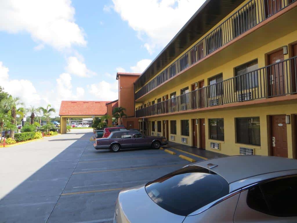 estacionamento com alguns carros e fachada amarela de três andares com várias portas e janelas do Budget Inn Of Orlando, um dos hostels em Orlando