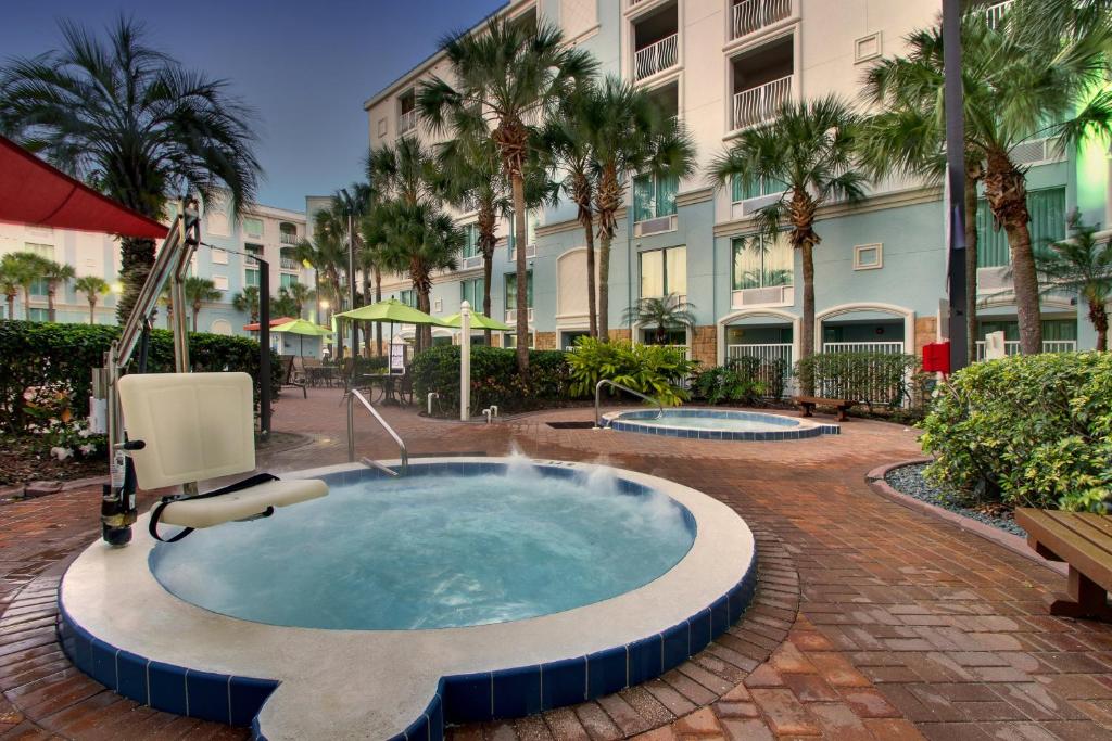 vista da área comum com a fachada atrás e algumas palmeiras ao redor, abaixo duas piscinas de hidro redondas, com uma delas tendo uma cadeira para PcDs entrarem com segurança no Holiday Inn Resort Orlando, um dos resorts em Orlando