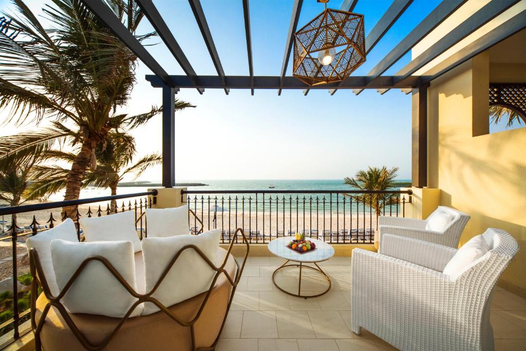 Varanda com poltronas e sofás em um dos quartos do Hilton Ras Al Khaimah Beach Resort com vista direta para a praia