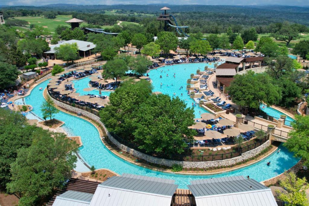 Vista aérea do JW Marriott San Antonio Hill Country Resort & Spa com diversas piscinas, árvores, pessoas dentro da água e muitas espreguiçadeiras, para representar onde ficar em San Antonio