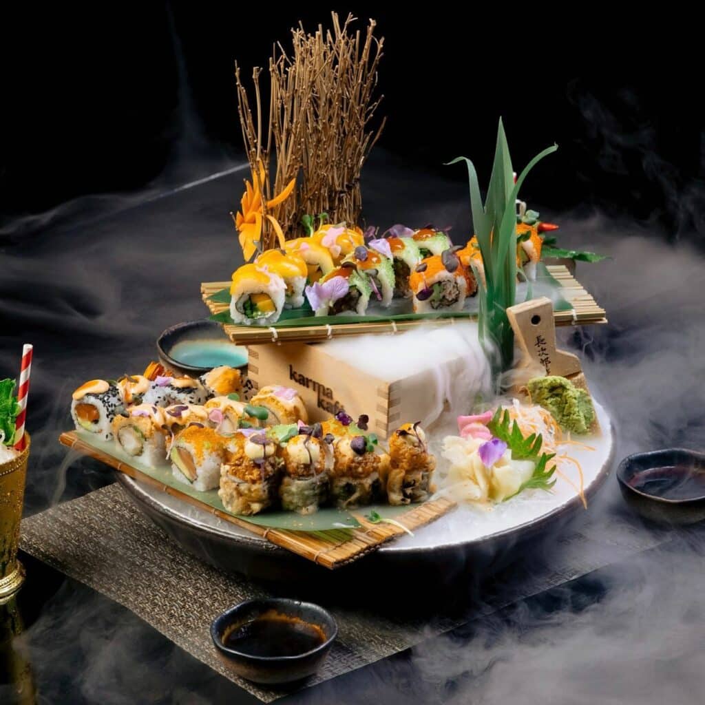 Uma prato do restaurante Karma Kafé by Buddha com diversos sushis montanhas em folhas de bambu
