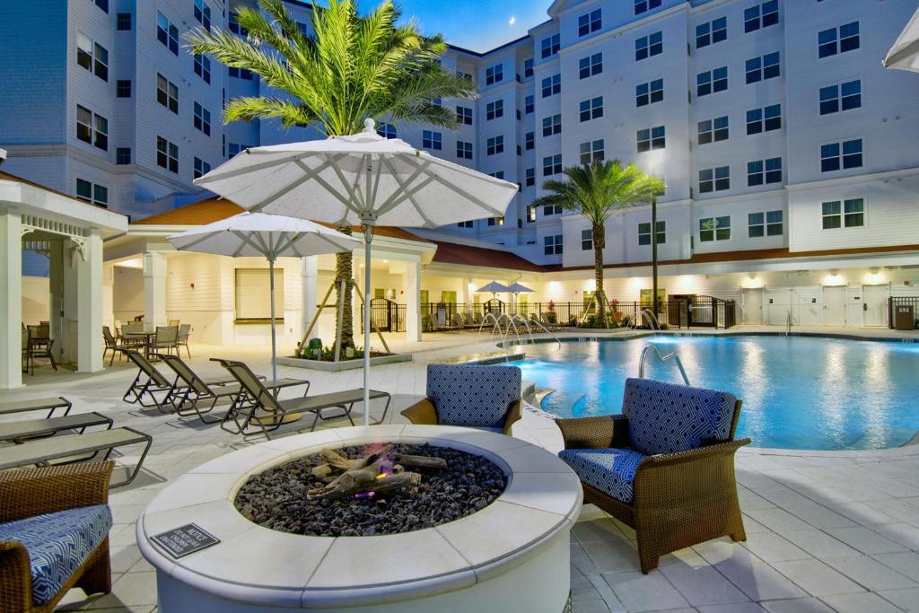 piscina e lareira com algumas palmeiras e poltronas ao redor com a fachada atrás do Residence Inn by Marriott Orlando, um dos hotéis perto da Disney