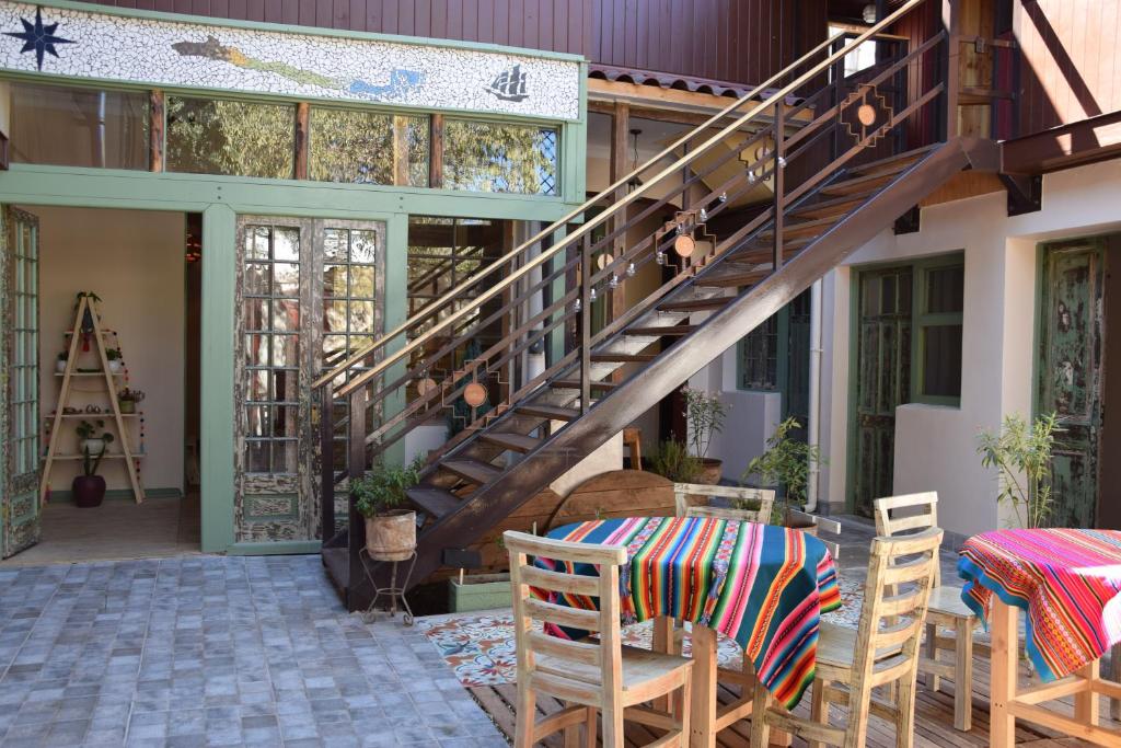 Área de lazer do Eco-Hostal Tambo Verde com mesas de madeira a frente e ao lado uma escada para a cobertura. Representa hostels em Santiago.