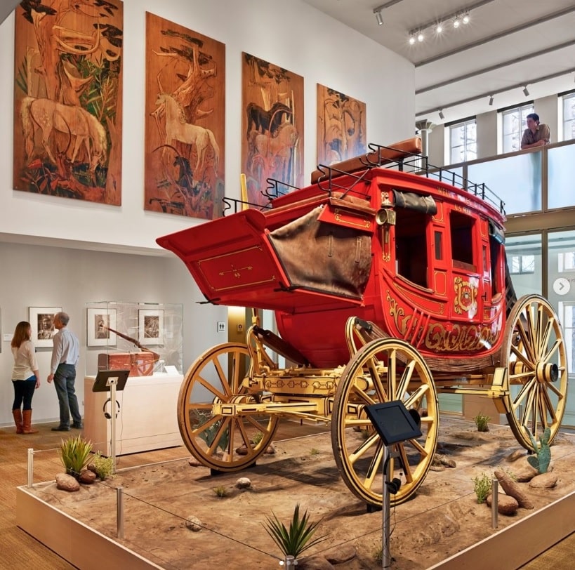 Uma enorme charrete vermelha com detalhes em dourado, incluindo duas rodas, exposta no Briscoe Western Art Museum