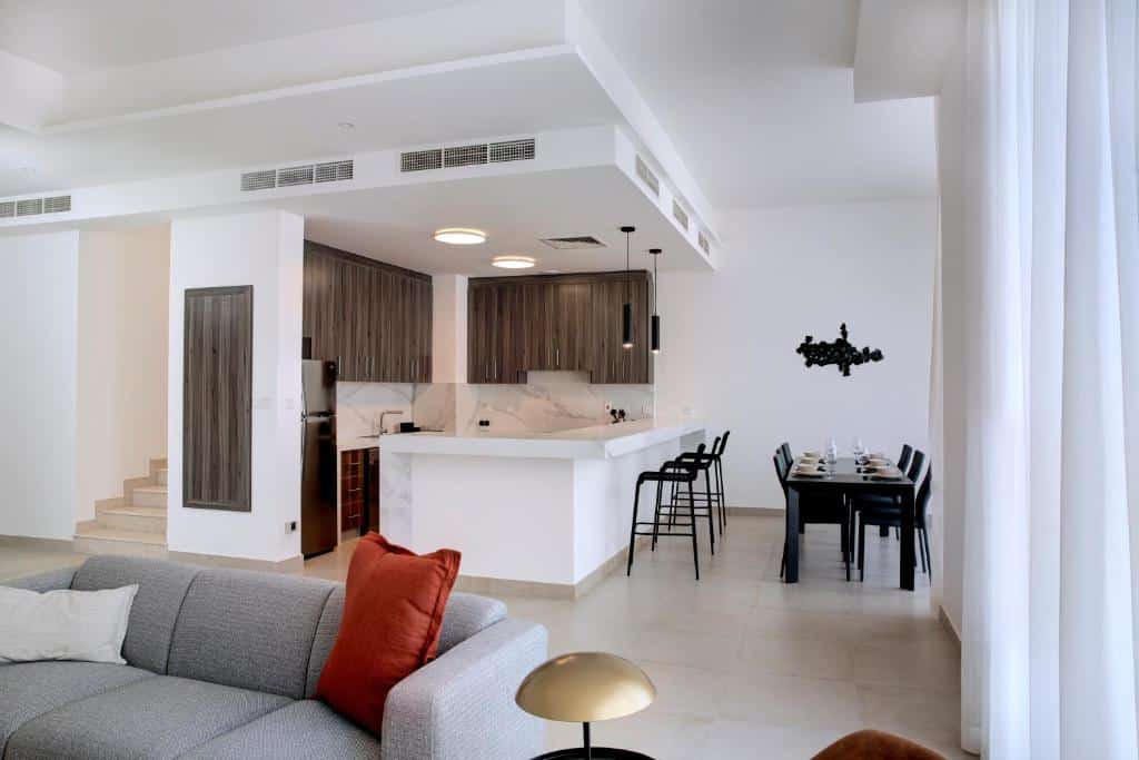 Sala de estar e de jantar do Olala Oasis Homes, em um dos ambientes há uma pequena cozinha com uma bancada, além de uma mesa com seis lugares, no outro ambiente tem um sofá e poltrona