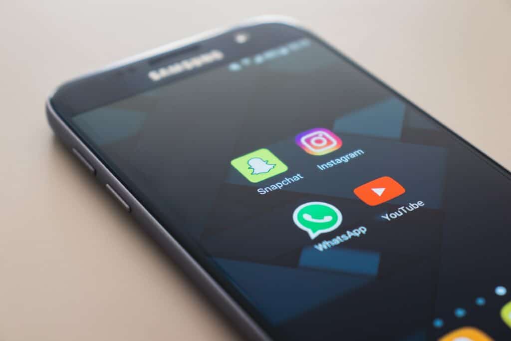Celular da Samsung sobre superfície plana, com ícones de quatro apps aparecendo, incluindo o Snapchat, o Instagram, o WhatsApp e o YouTube