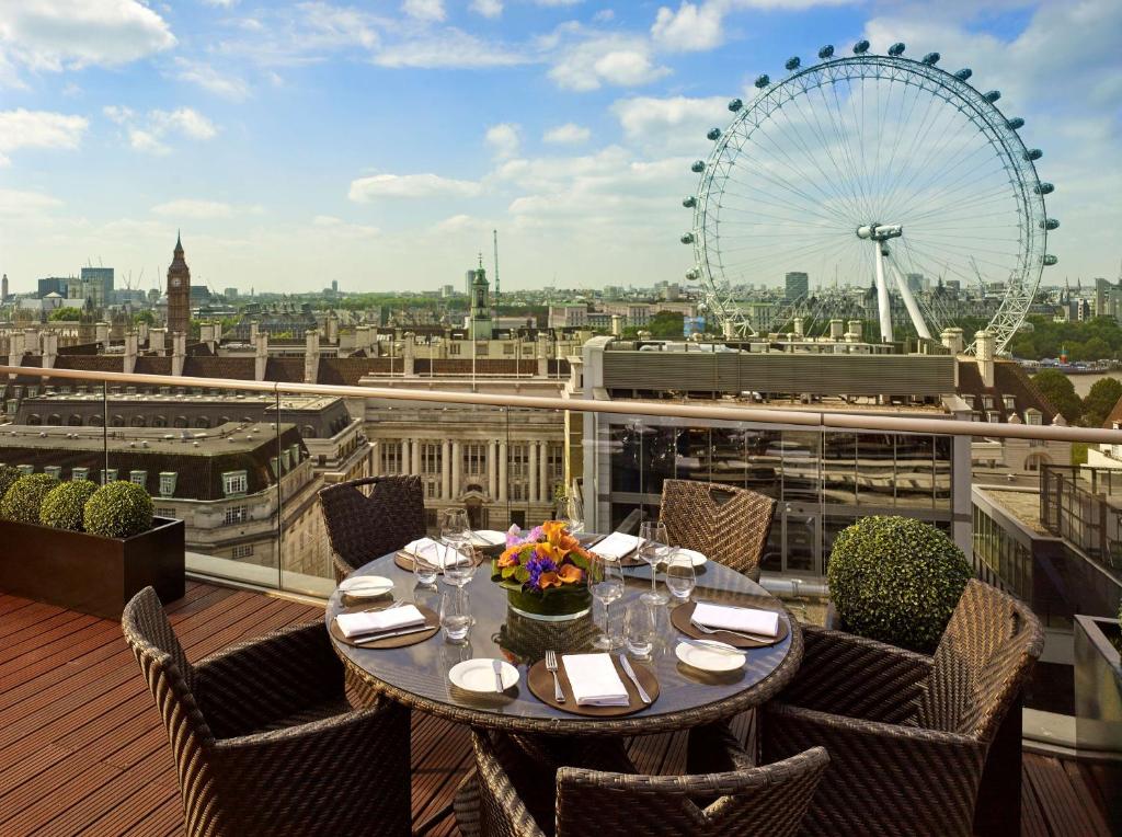 Sacada do Park Plaza County Hall London com uma mesa redonda com cadeiras com vista direta para a London Eye, para representar onde ficar em Londres