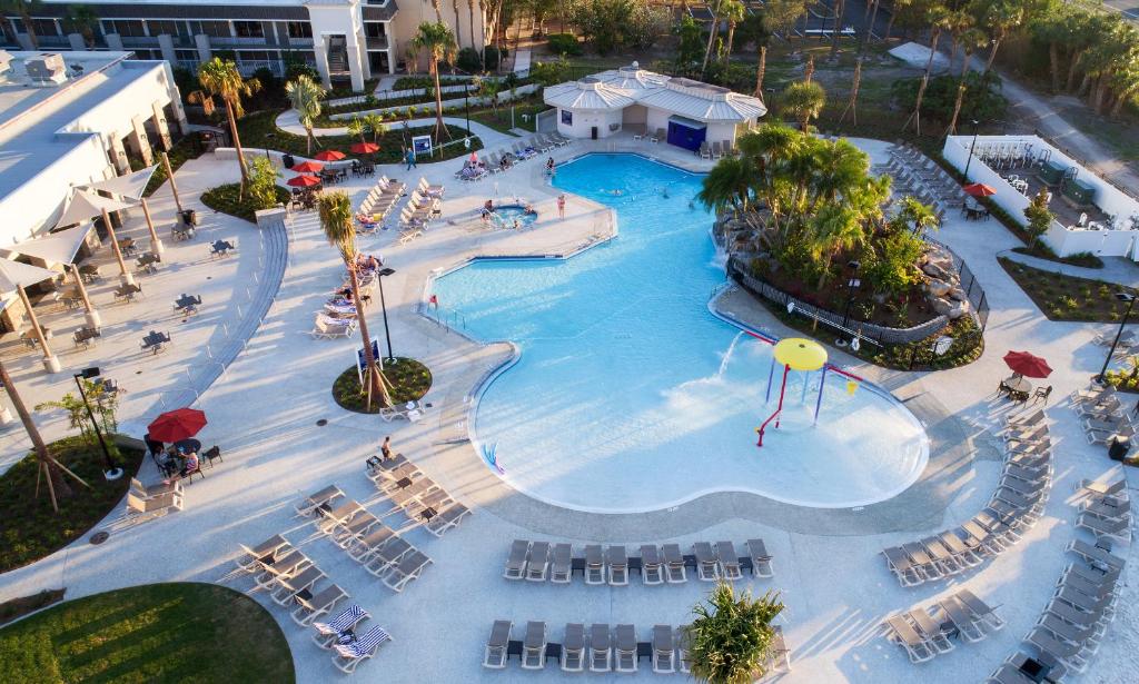 muitas cadeiras e árvores ao redor de uma piscina grande de bordas arredondadas do Avanti Palms Resort And Conference Center, uma das opções aos hostels em Orlando