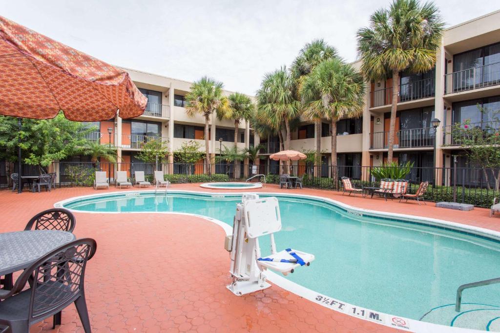 fachada do hotel atrás e, abaixo, a piscina de bordas sinuosas do Days Inn & Suites by Wyndham Orlando Airport, um dos hostels em Orlando