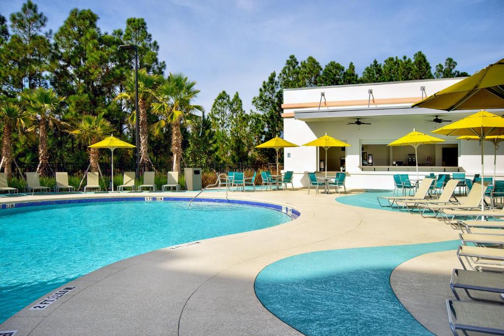 piscina do Fairfield by Marriott Inn & Suites Orlando, um dos hotéis perto da Disney, com bordas arredondadas e detalhes que lembram ondas perto das cadeiras de praia ao redor