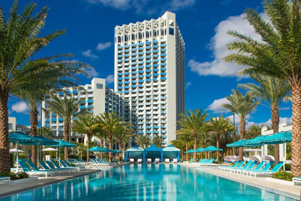 fachada alta com palmeiras abaixo e uma piscina em tons verdes no Hilton Orlando Buena Vista Palace um dos hotéis da Disney em Orlando
