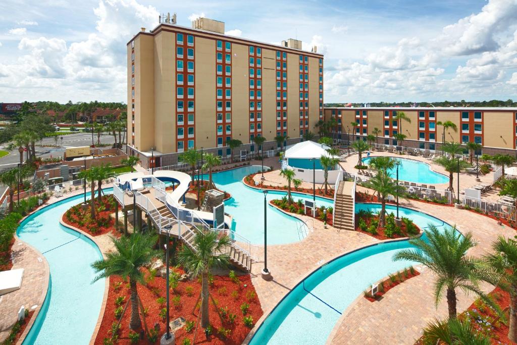 área externa com a fachada e uma piscina grande que se estende pela área com alguns tobogãs e mais no Red Lion Hotel Orlando Lake Buena Vista South- Near Disney, uma das opções dos hostels em Orlando