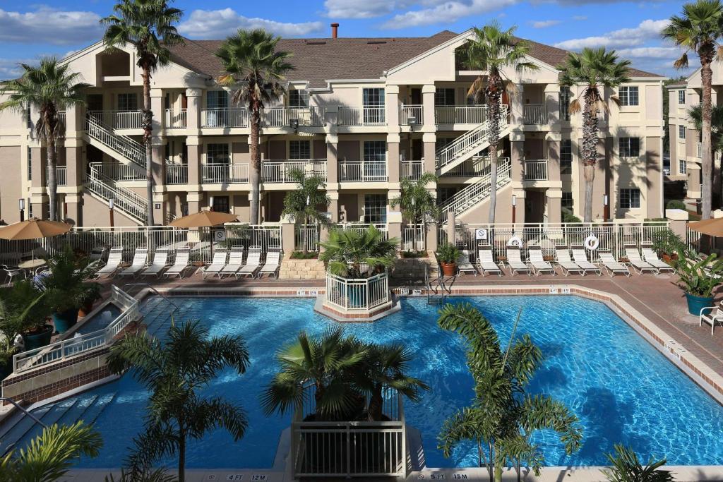 fachada imponente com várias janelinhas e palmeiras na frente de uma piscina enorme no Sonesta ES Suites Orlando - Lake Buena Vista, um dos hotéis perto da Disney