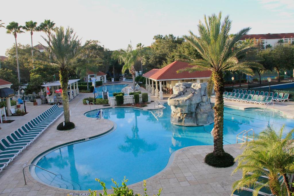 piscina com bordas arredondadas no ambiente externo com algumas palmeiras, muitas cadeiras de praia e um pequeno tobogã no meio no Star Island Resort and Club - Near Disney, um dos hotéis em Kissimmee