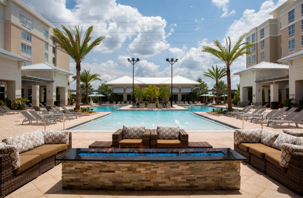 piscina com algumas palmeiras e um sofá baixo que dá vista para o ambiente aberto no TownePlace Suites Orlando, um dos hotéis perto da Disney
