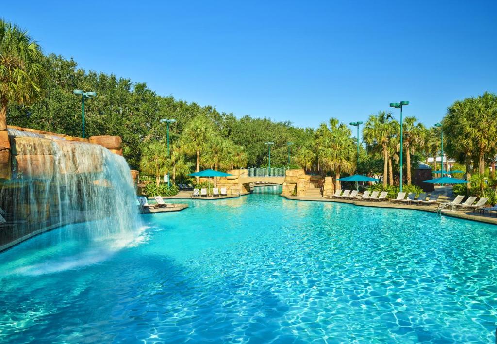 piscina com cascata e cadeiras de praia ao redor, com árvores ao fundo no Walt Disney World Swan, um dos hotéis da Disney em Orlando