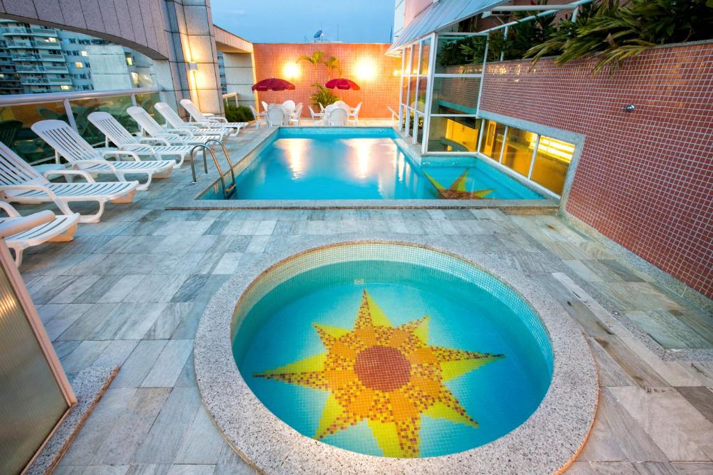 Uma piscina pequena na frente redonda, com uma estrela no fundo, atrás uma piscina maior e no lado esquerdo cadeiras. Foto para ilustrar post sobre hotéis perto do Consulado Americano no Rio de Janeiro.