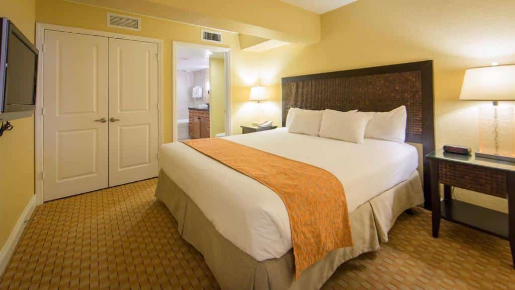 quarto do Holiday Inn Club Vacations At Orange Lake Resort com cama de casal, mesinha e luminária de ambos os lados, com guarda-roupa e banheiro