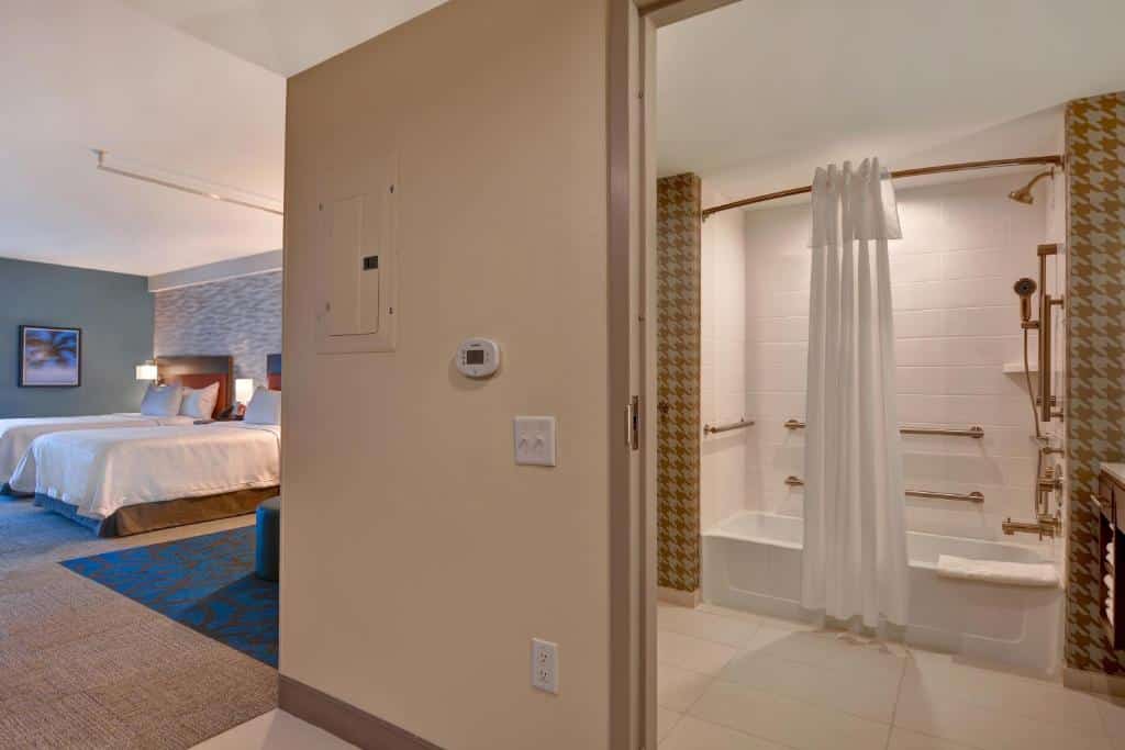quarto do Home2 Suites By Hilton Orlando Flamingo Crossings, FL com cama de casal em um ambiente amplo com cama de casal e sofá e um banheiro com adaptações para PcDs com barras de apoio