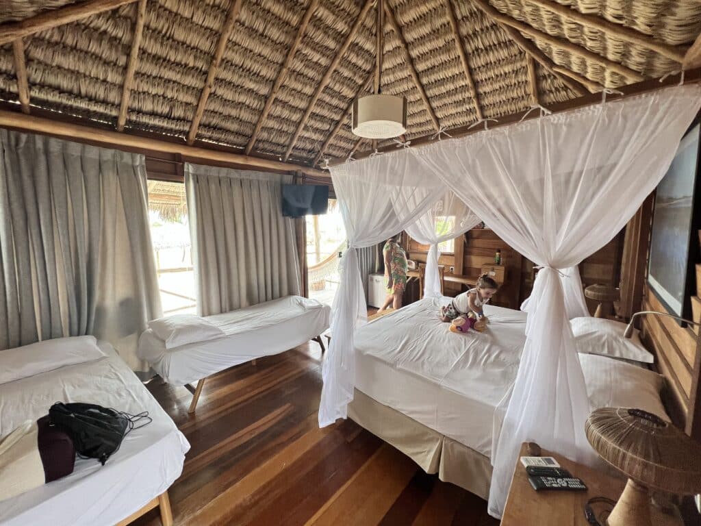 quarto do bangalo frete mar  na Pousada BGK- cama com lençol branco e criança em cima da cama.