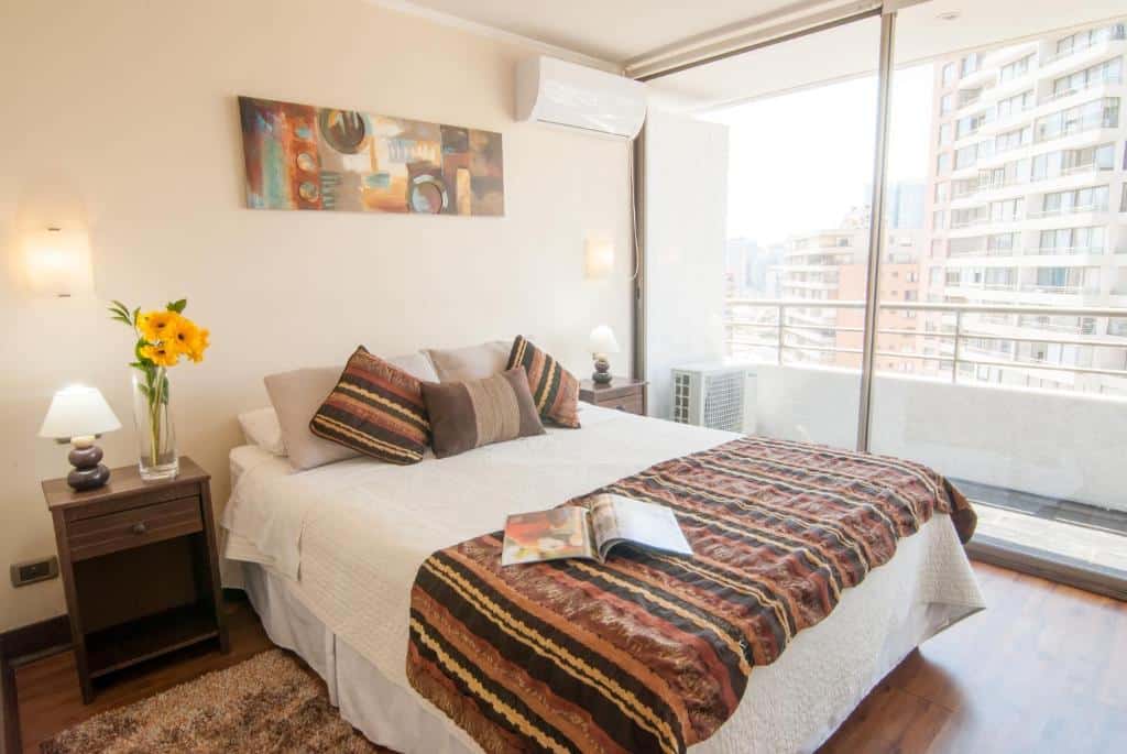 Quarto do Departamentos Apartviews Cordillera com cama de casal no centro do quarto com duas cômodas ao lado.