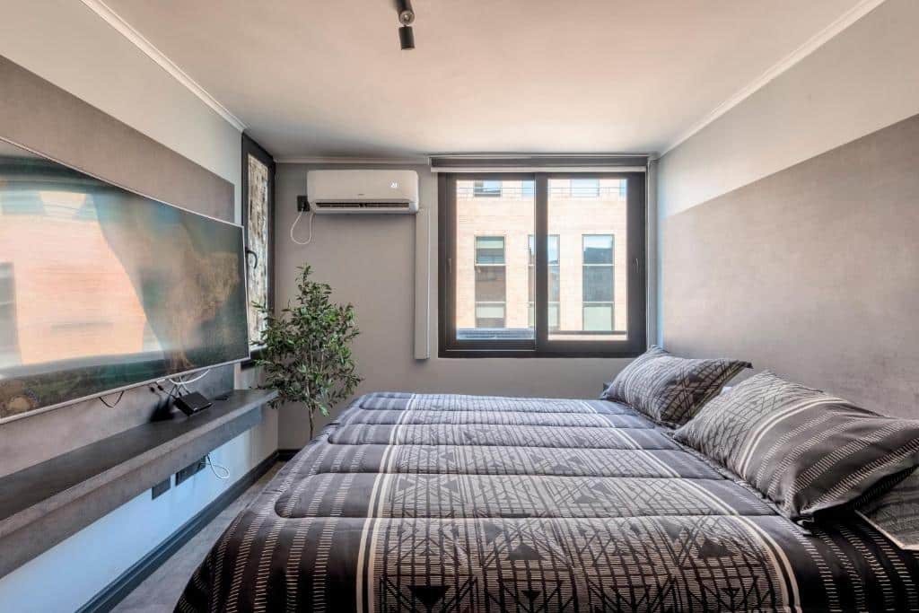 Quarto do Encomenderos Design Tech Comfort & Location com cama de casal e em frente a cama uma TV.