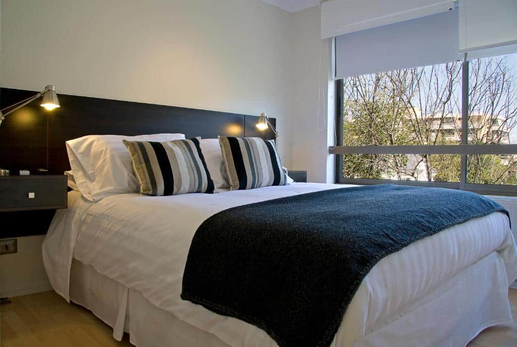 Quarto do Heidelberg Haus Apart Hotel com cama de casal e do lado esquerdo uma janela panorâmica.