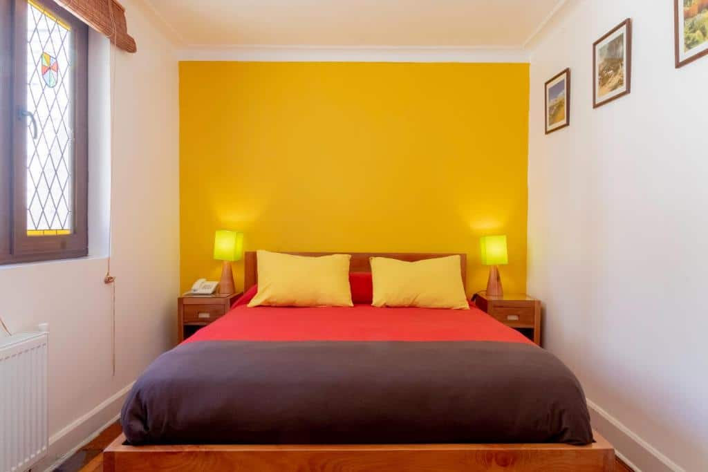 Quarto do Hostal Rio Amazonas com cama de casal no centro do quarto, ao lado da cama duas cômodas de madeira com luminária.