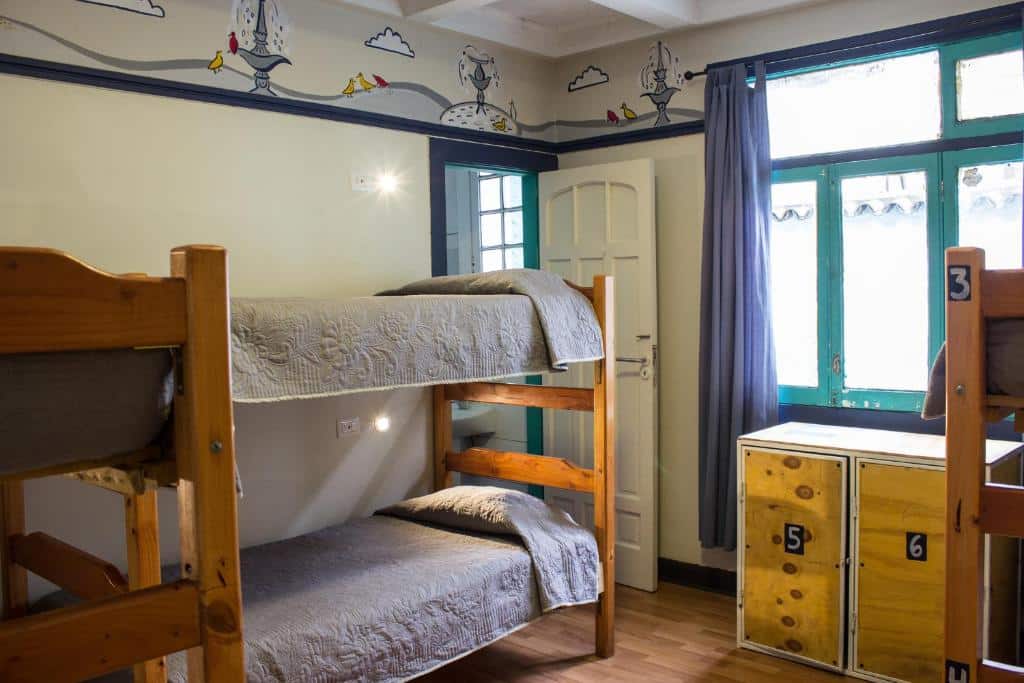 Quarto compartilhado do Hostal Forestal com três camas de beliche no ambiente e um armário a frente.