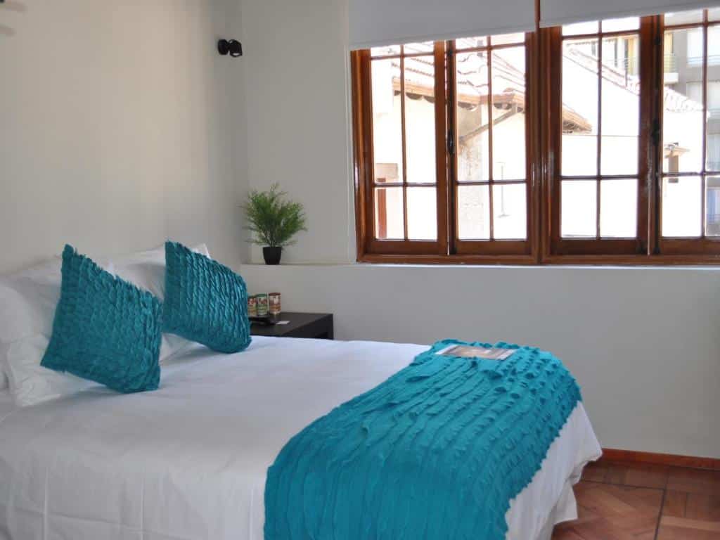 Quarto do Hotel CasaDeTodos com cama de casal no centro uma cômoda de madeira do lado esquerdo do quarto perto da janela.